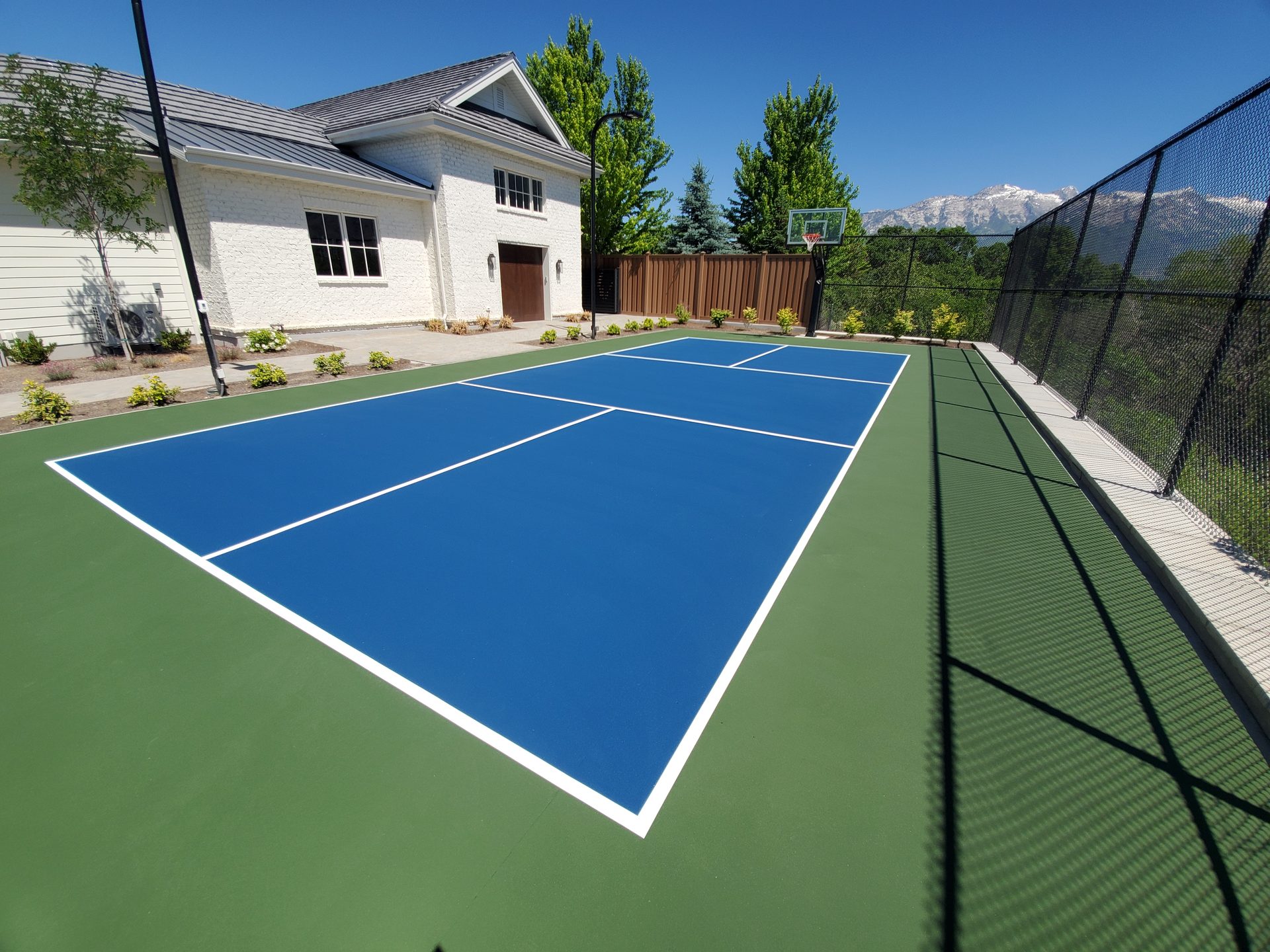Blue pickleball court with mountain backdrop and white home