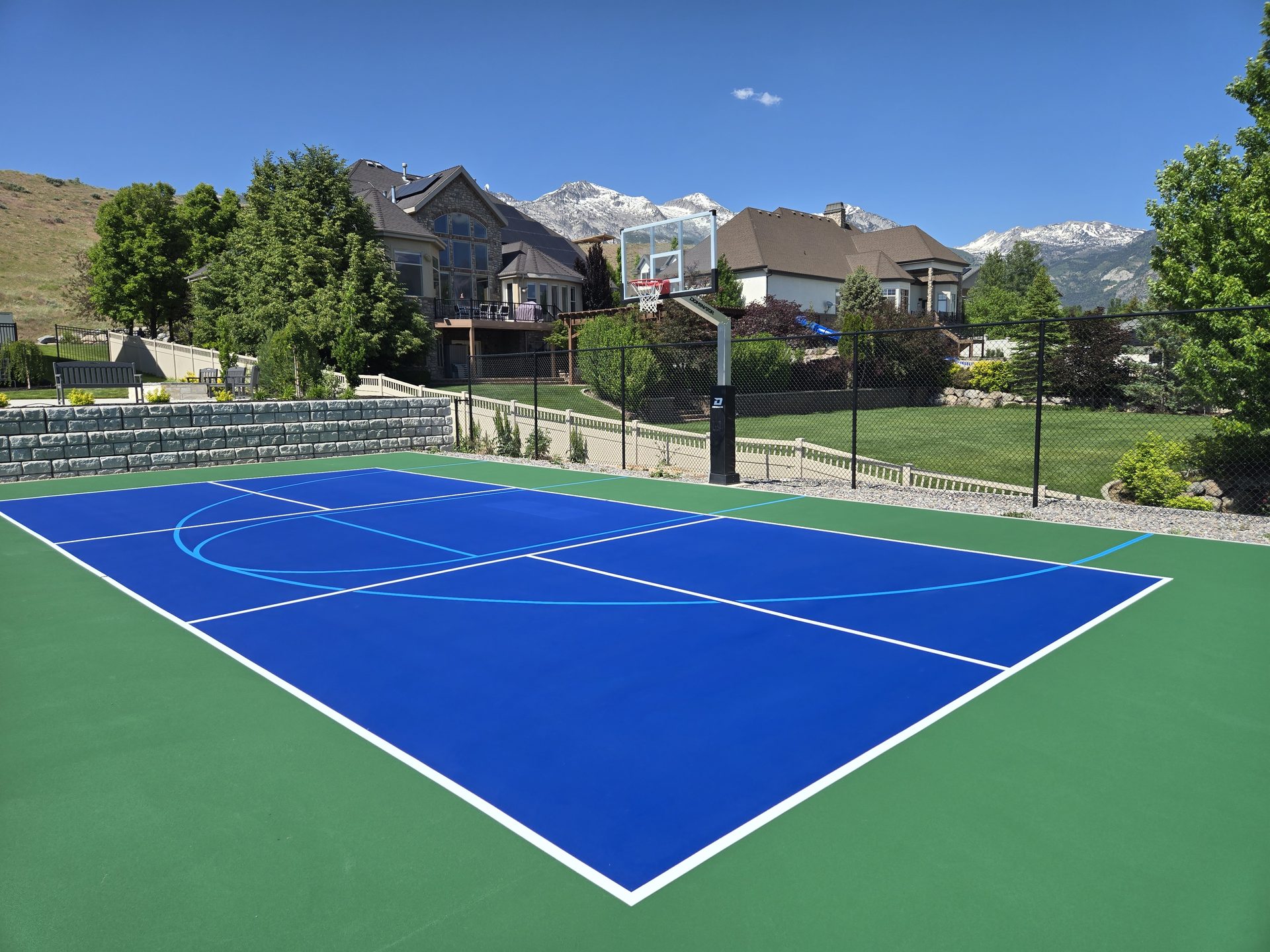 Blue backyard sport court with snow-capped Wasatch mountains in the background